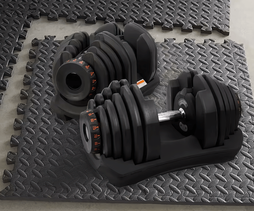 Black EVA foam gym mats with adjustable dumbbells, showcasing a non-slip interlocking floor solution for home exercise areas.